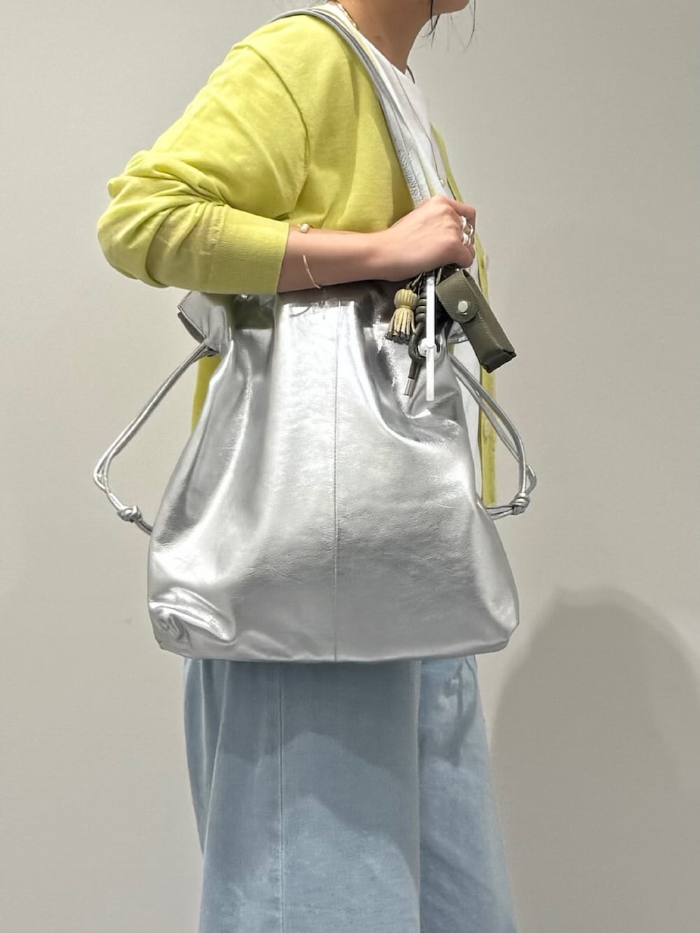 シルバー系のトートバッグ、ブラック系のローファー、ブルー系のデニムパンツを着用したレディースの春コーディネートの7枚目の写真