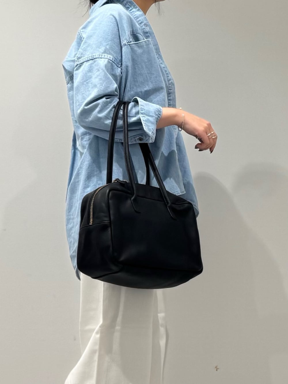 ブラック系のボストンバッグ、ホワイト系のデニムパンツ、ブルー系のシャツ/ブラウスを着用したレディースの春コーディネートの6枚目の写真