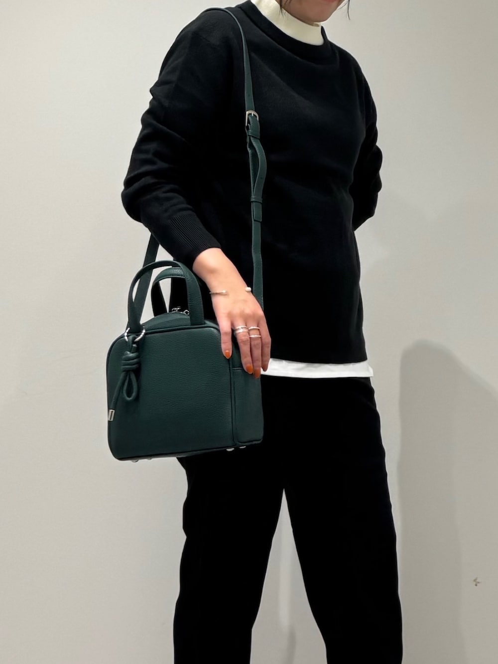 グリーン系のボストンバッグ、ブラック系のニット/セーター、ホワイト系のTシャツ/カットソーを着用したレディースの冬コーディネートの6枚目の写真