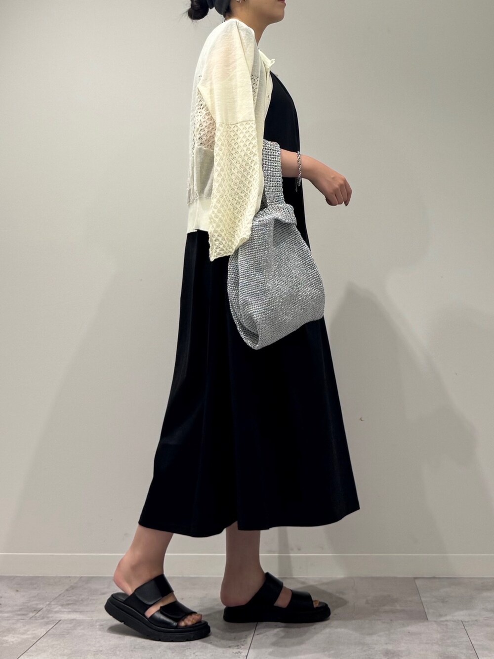 シルバー系のかごバッグ、ブラック系のワンピース、ホワイト系のカーディガン/ボレロを着用したレディースの秋コーディネートの2枚目の写真