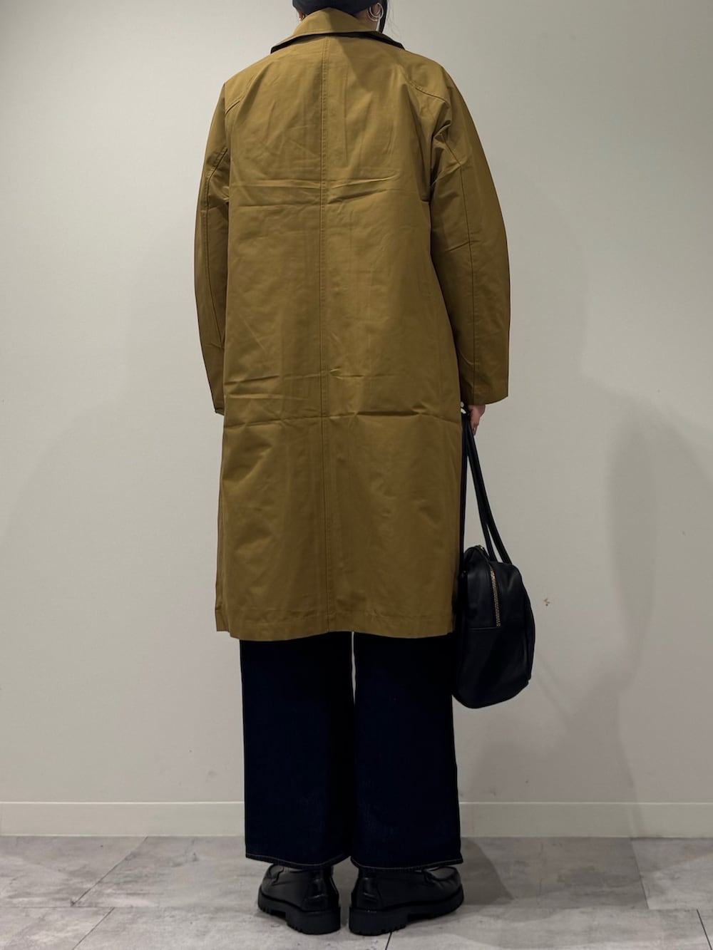 ブラック系のボストンバッグ、ベージュ系のダウンジャケット/コート、ブルー系のデニムパンツを着用したレディースの冬コーディネートの4枚目の写真