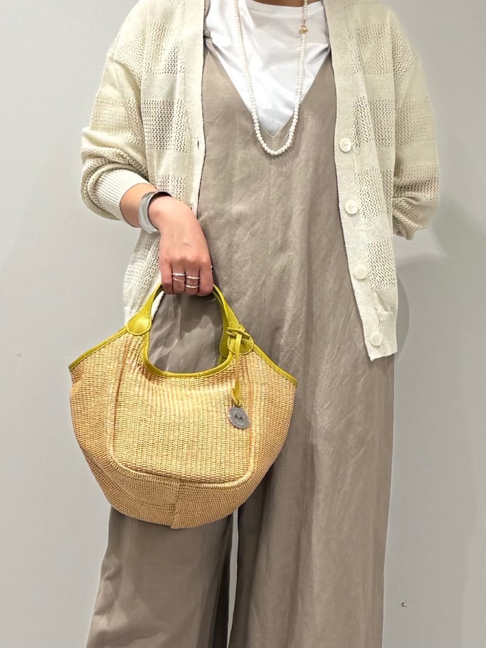 ベージュ系のサロペット/オーバーオール、ホワイト系のカーディガン/ボレロ、ベージュ系のかごバッグを着用したレディースの春コーディネートの9枚目の写真