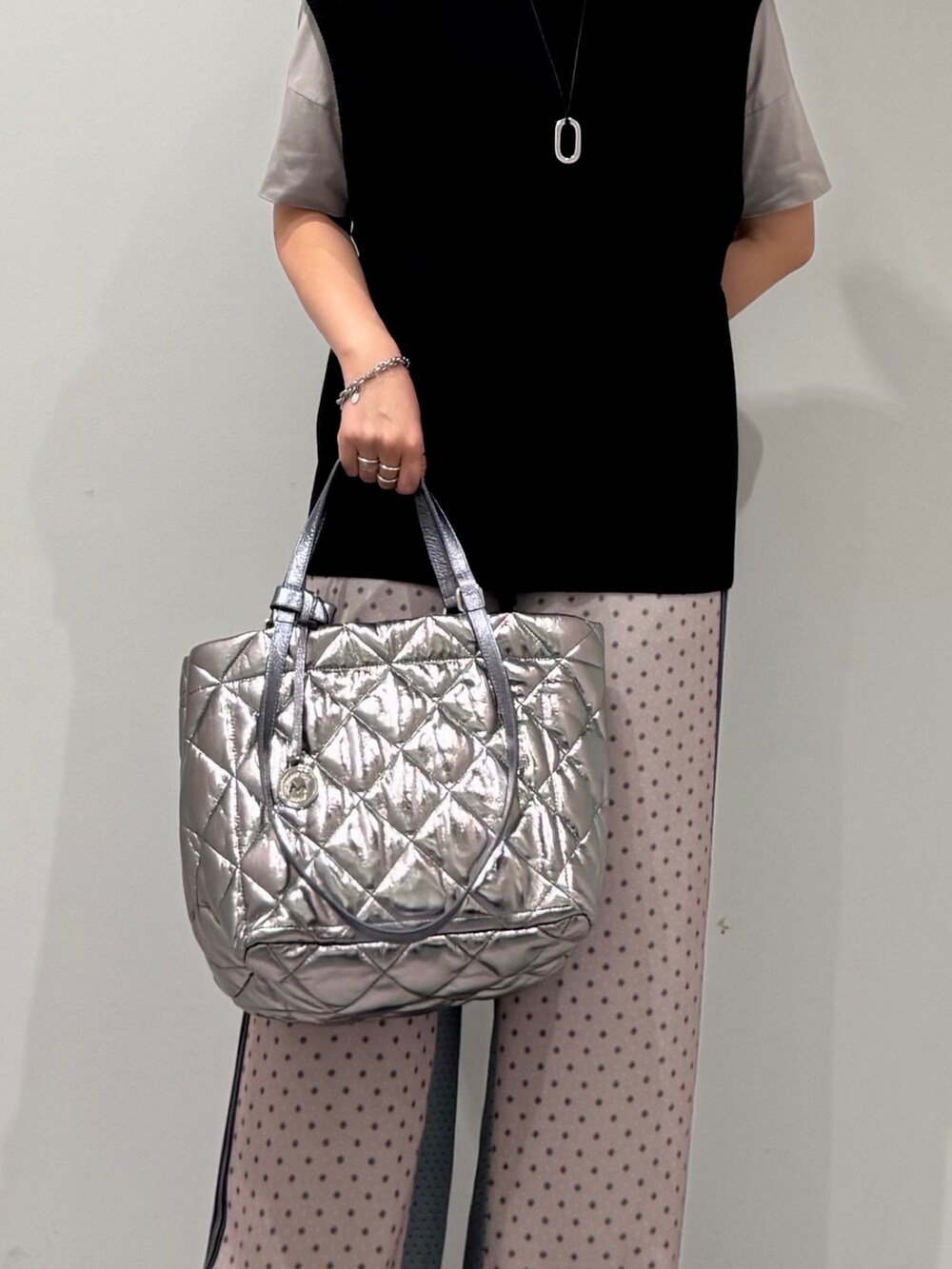 シルバー系のトートバッグ、ベージュ系のその他パンツ、ブラック系のベストを着用したレディースの秋コーディネートの7枚目の写真