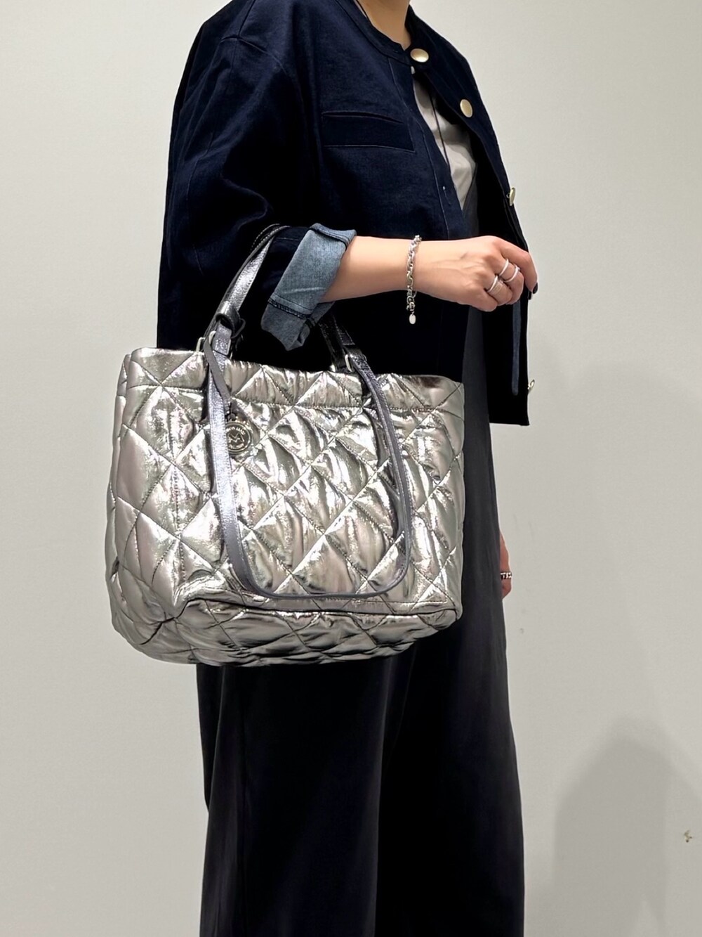 シルバー系のトートバッグ、グレー系のサロペット/オーバーオール、グレー系のTシャツ/カットソーを着用したレディースの秋コーディネートの6枚目の写真