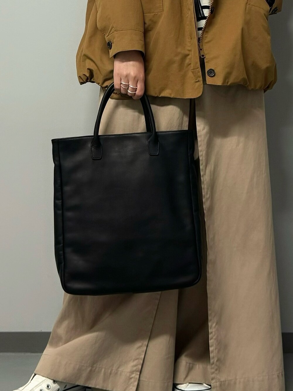 ブラック系のトートバッグ、ベージュ系のブルゾン、ブラック系のTシャツ/カットソーを着用したレディースの秋コーディネートの7枚目の写真