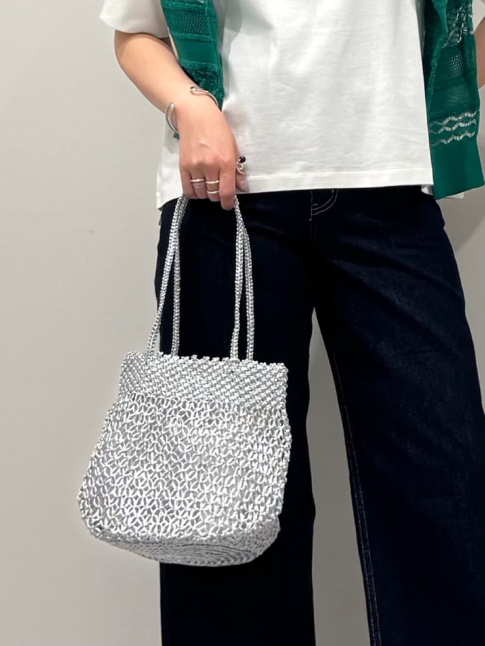 シルバー系のかごバッグ、ブルー系のデニムパンツ、ブラック系のサンダルを着用したレディースの春コーディネートの7枚目の写真