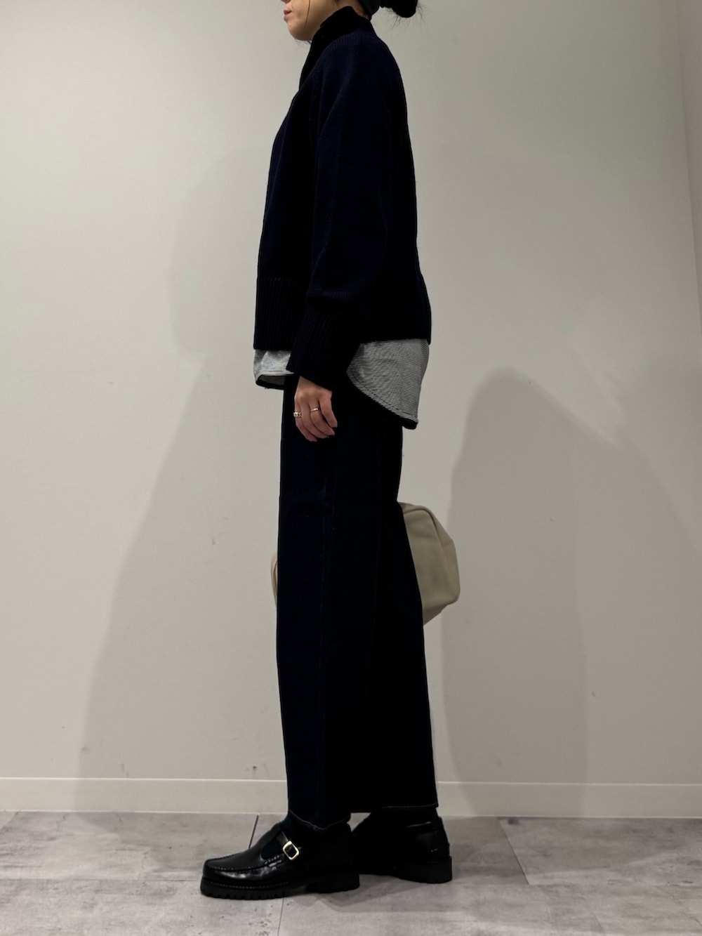 ベージュ系のボストンバッグ、ブルー系のデニムパンツ、ブラック系のローファーを着用したレディースの冬コーディネートの5枚目の写真