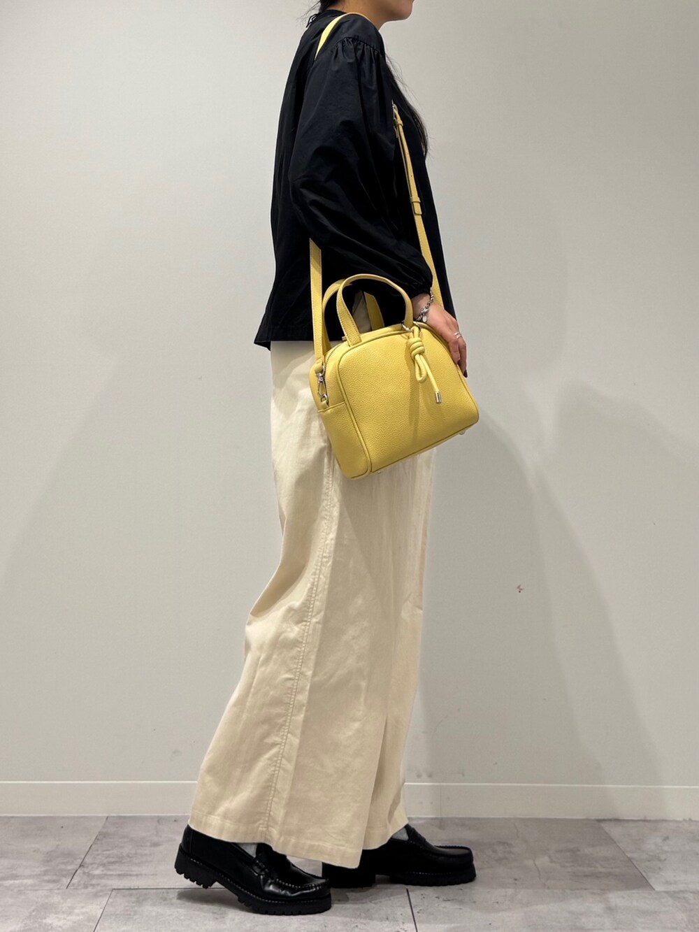 イエロー系のボストンバッグ、ブラック系のローファー、ブラック系のシャツ/ブラウスを着用したレディースの秋コーディネートの2枚目の写真
