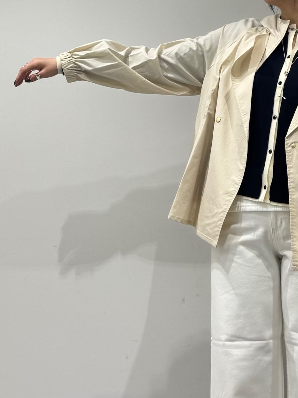 ブラック系のボストンバッグ、ホワイト系のトレンチコート、ホワイト系のデニムパンツを着用したレディースの冬コーディネートの6枚目の写真