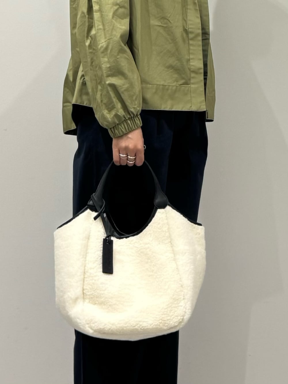 ホワイト系のトートバッグ、ブルー系のチノパンツ、グリーン系のブルゾンを着用したレディースの秋コーディネートの8枚目の写真