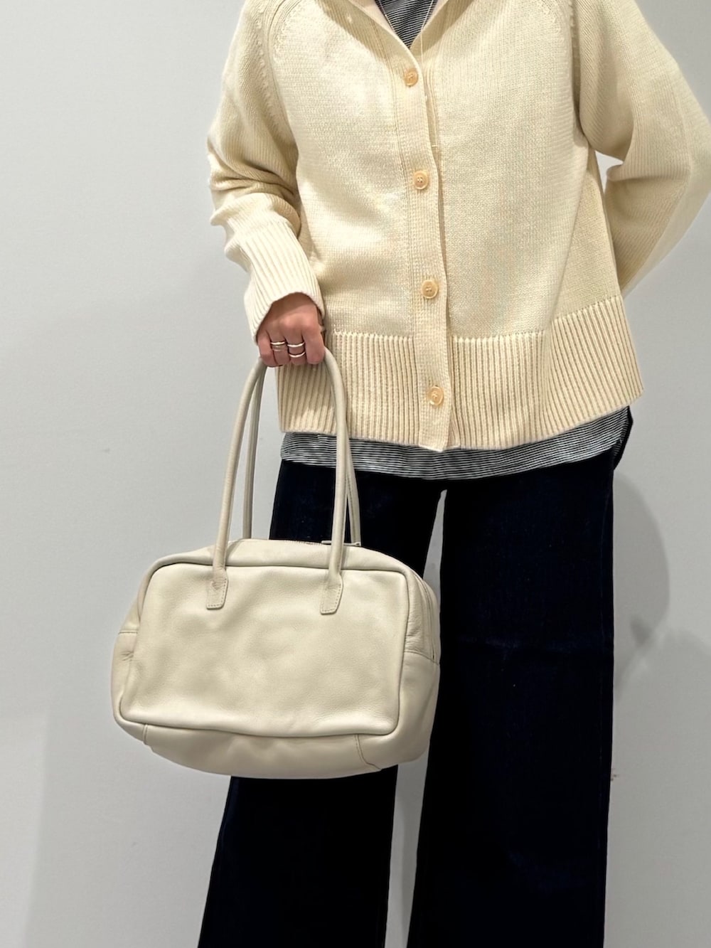 ベージュ系のボストンバッグ、ブルー系のデニムパンツ、ブラック系のローファーを着用したレディースの冬コーディネートの7枚目の写真