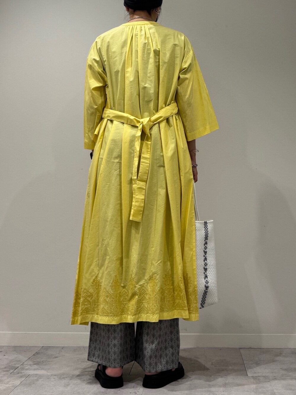 ホワイト系のかごバッグ、イエロー系のワンピース、ベージュ系のその他パンツを着用したレディースの夏コーディネートの5枚目の写真