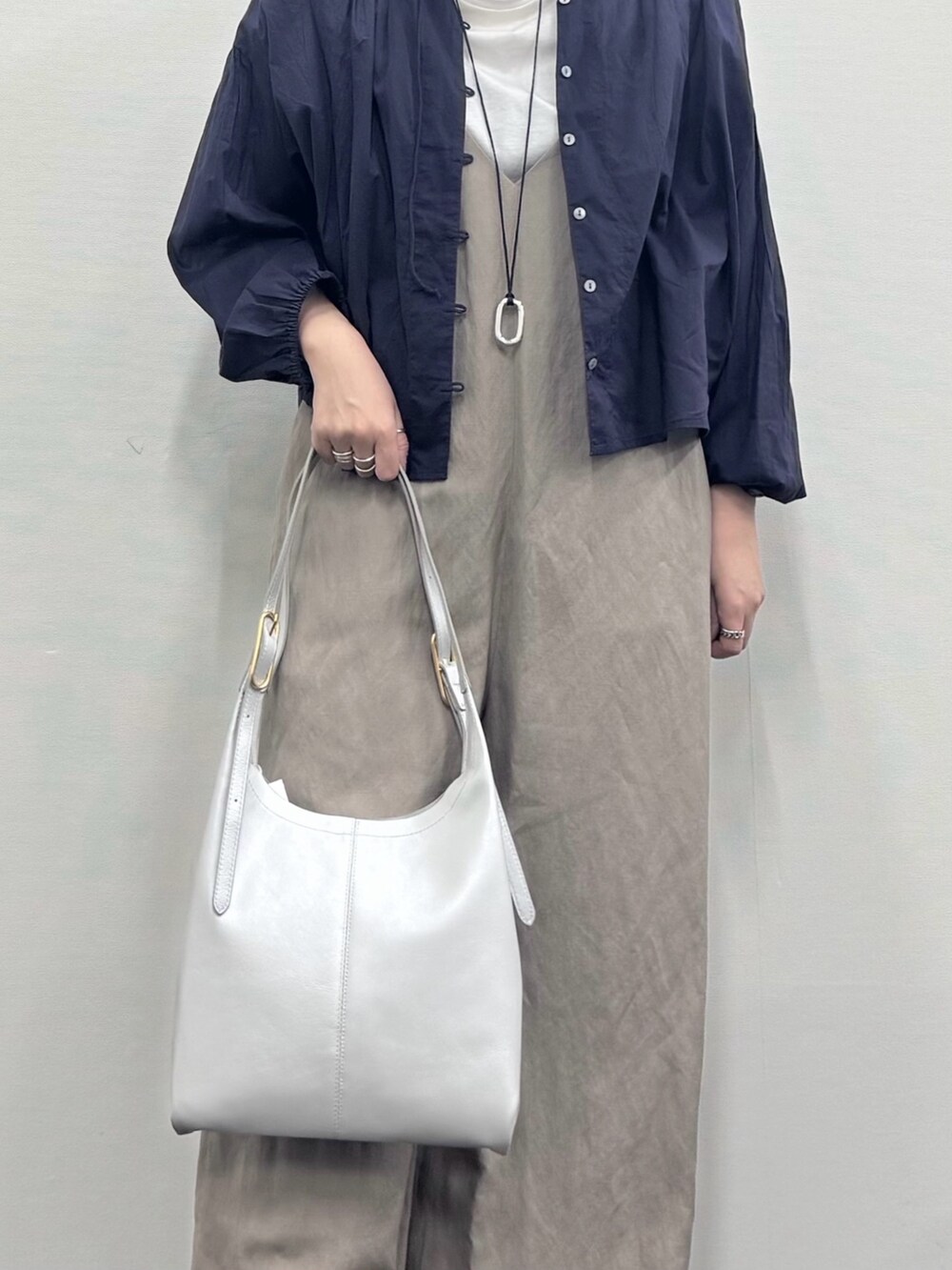 シルバー系のトートバッグ、ベージュ系のサロペット/オーバーオール、ホワイト系のTシャツ/カットソーを着用したレディースの春コーディネートの7枚目の写真