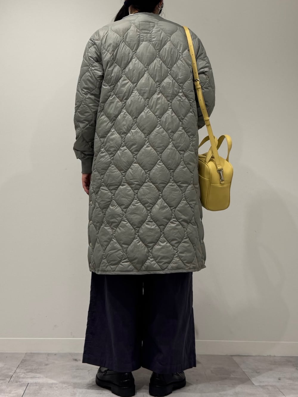 イエロー系のボストンバッグ、ブラック系のローファー、ホワイト系のベストを着用したレディースの秋コーディネートの4枚目の写真