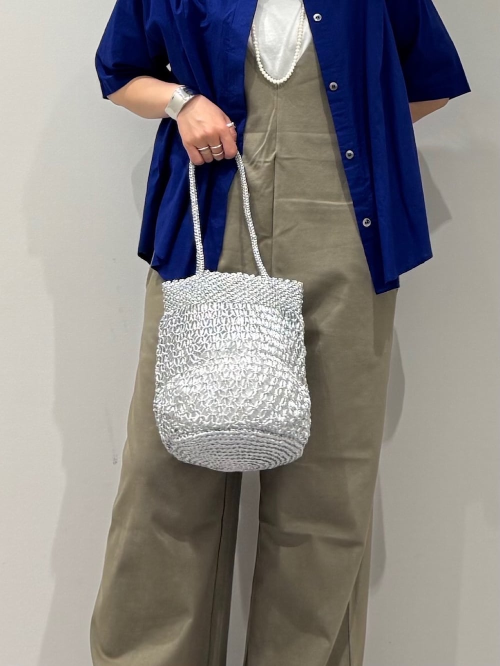 シルバー系のかごバッグ、グリーン系のサロペット/オーバーオール、ブルー系のシャツ/ブラウスを着用したレディースの夏コーディネートの7枚目の写真