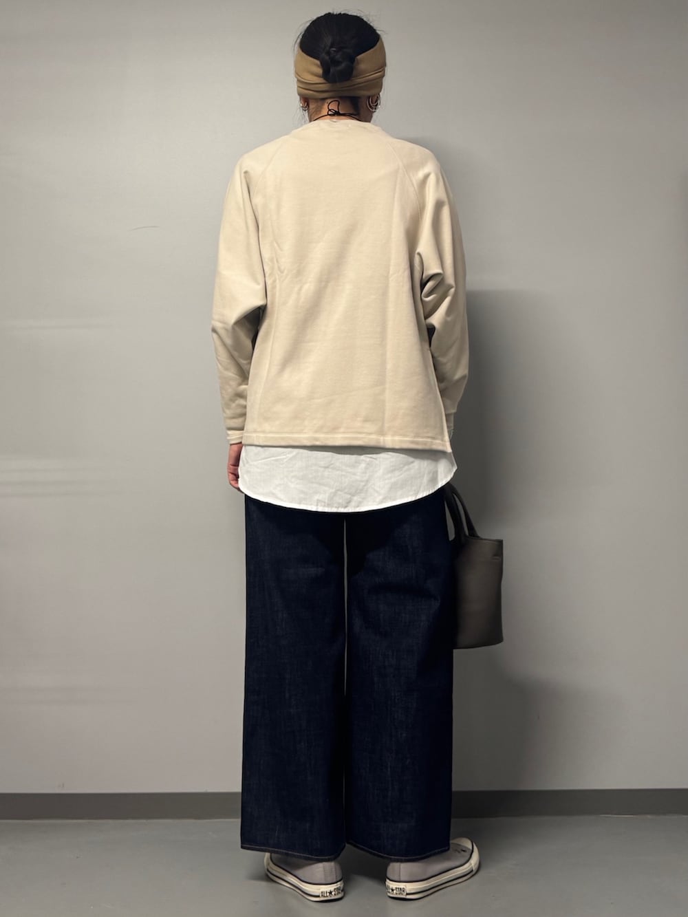 ベージュ系のスウェット、ブルー系のデニムパンツ、グレー系のトートバッグを着用したレディースの冬コーディネートの2枚目の写真