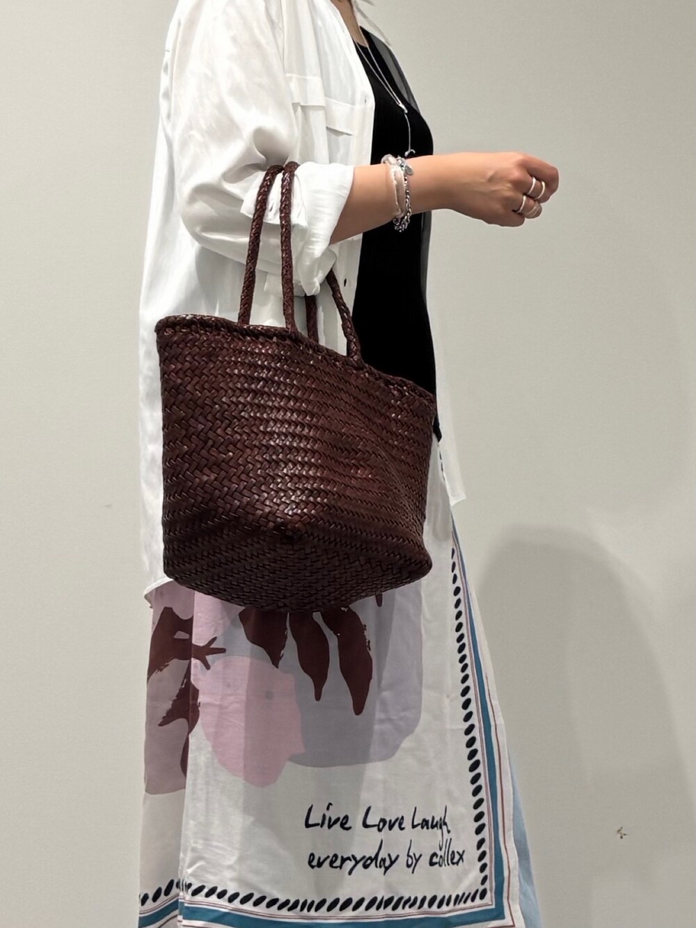 ブラウン系のトートバッグ、ブルー系のデニムパンツ、ブラック系のサンダルを着用したレディースの秋コーディネートの8枚目の写真