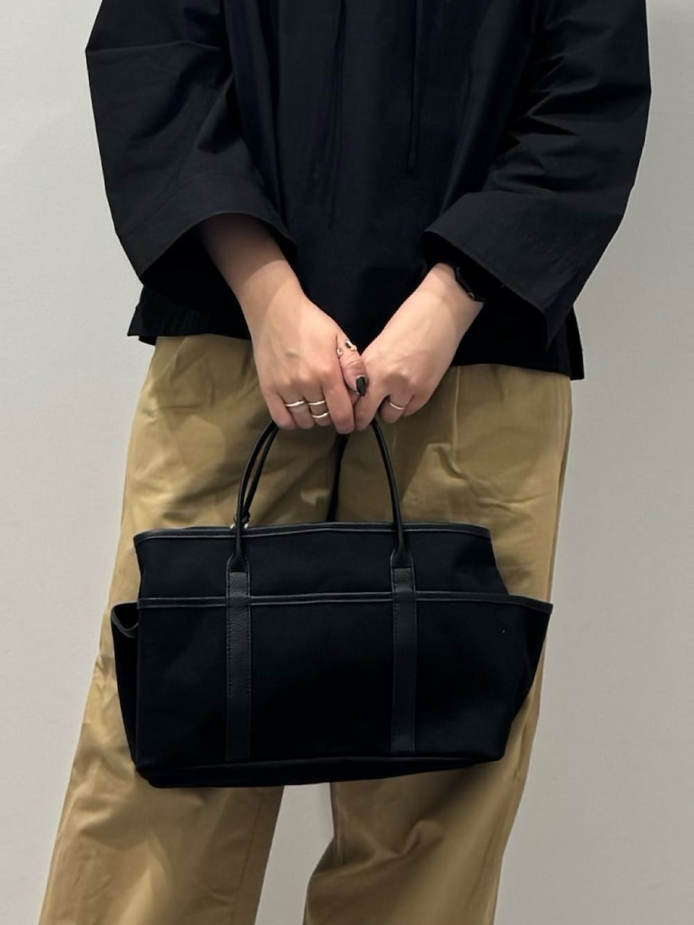 ブラック系のスニーカー、ベージュ系のチノパンツ、ブラック系のシャツ/ブラウスを着用したレディースの秋コーディネートの6枚目の写真