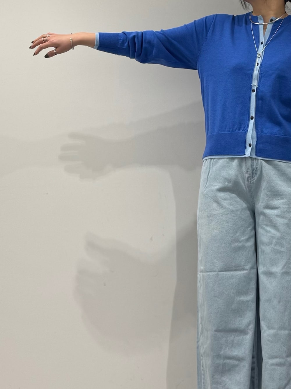 シルバー系のショルダーバッグ、ブルー系のカーディガン/ボレロ、ブルー系のデニムパンツを着用したレディースの冬コーディネートの6枚目の写真