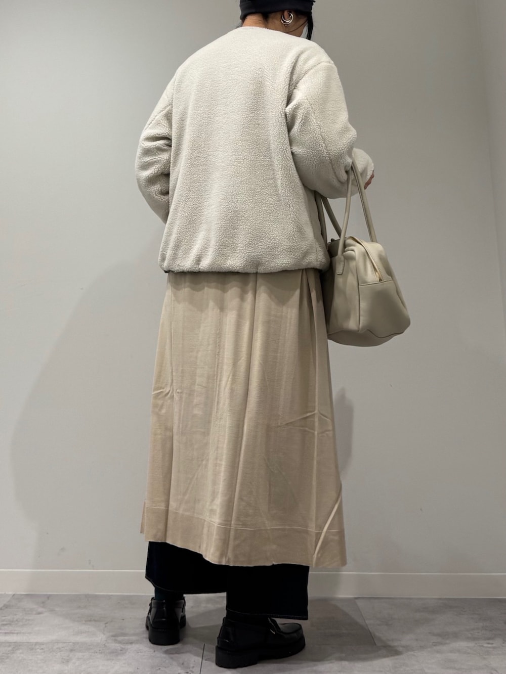 ベージュ系のボストンバッグ、ベージュ系のワンピース、ブルー系のデニムパンツを着用したレディースの春コーディネートの4枚目の写真