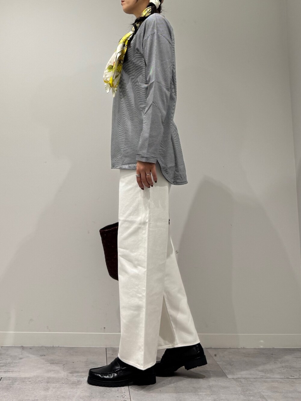 ブラウン系のトートバッグ、ホワイト系のデニムパンツ、ブラック系のローファーを着用したレディースの秋コーディネートの5枚目の写真