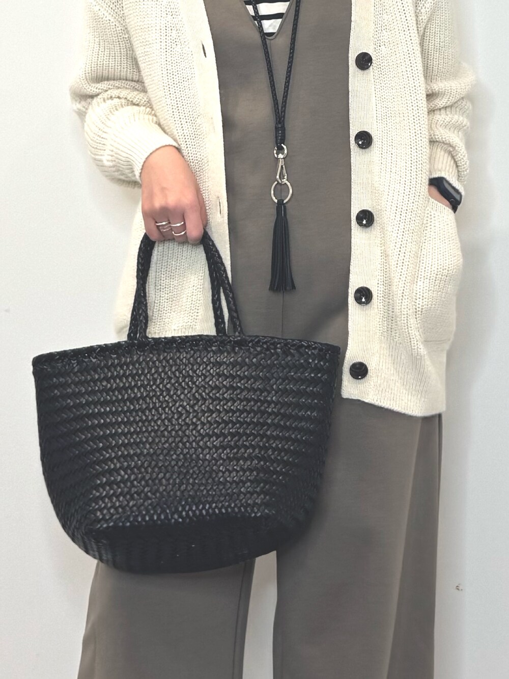 ブラック系のトートバッグ、ブラウン系のサロペット/オーバーオール、ホワイト系のカーディガン/ボレロを着用したレディースの冬コーディネートの8枚目の写真