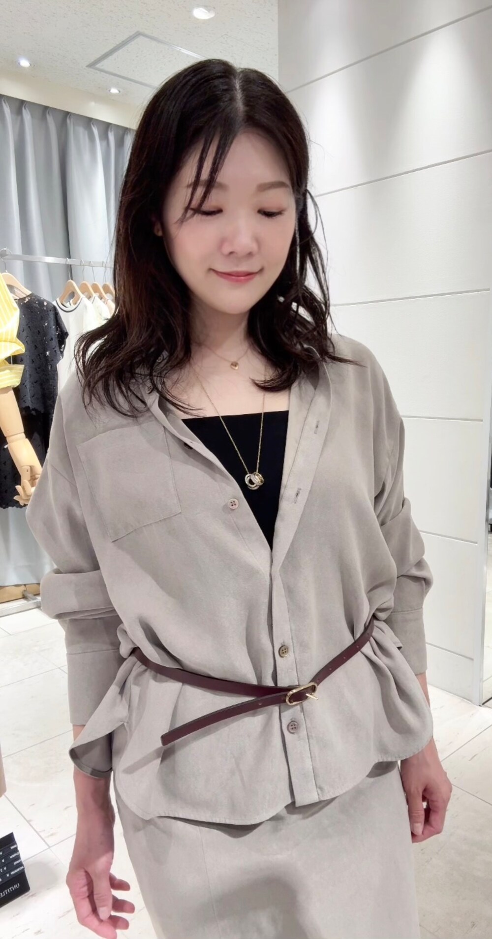 ベージュ系のシャツ/ブラウス、ベージュ系のスカート、ブラック系のタンクトップを着用したレディースの秋コーディネートの2枚目の写真