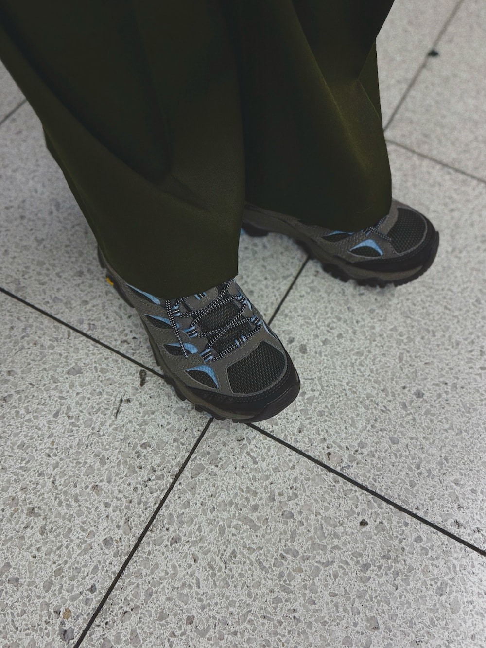 グリーン系のスラックス、グレー系のスニーカー、ブラック系のニット/セーターを着用したレディースの冬コーディネートの3枚目の写真