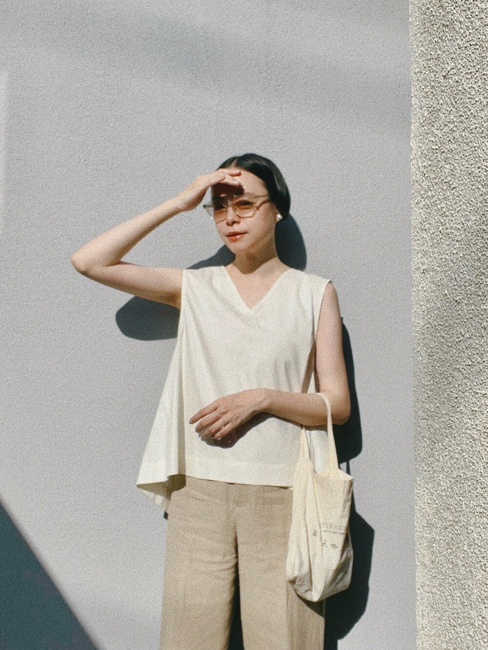 ホワイト系のシャツ/ブラウス、ベージュ系のパンツ、ブラック系のサンダルを着用したレディースの夏コーディネートの2枚目の写真