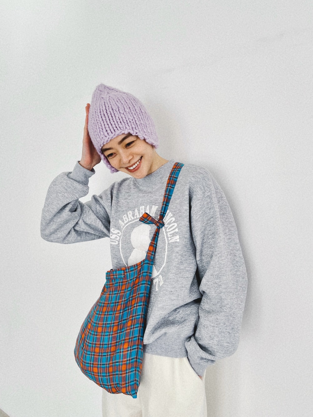 ホワイト系のスニーカー、その他のトートバッグ、パープル系のニットキャップ/ビーニーを着用したレディースの冬コーディネートの2枚目の写真