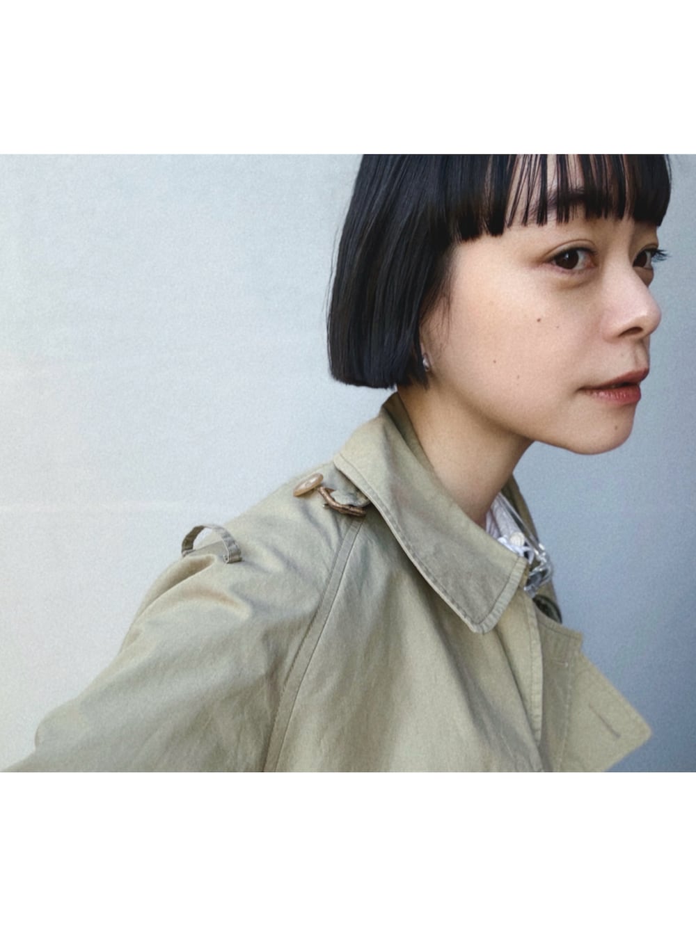 ベージュ系のトレンチコート、ホワイト系のカーディガン/ボレロ、ホワイト系のワンピースを着用したレディースの春コーディネートの2枚目の写真