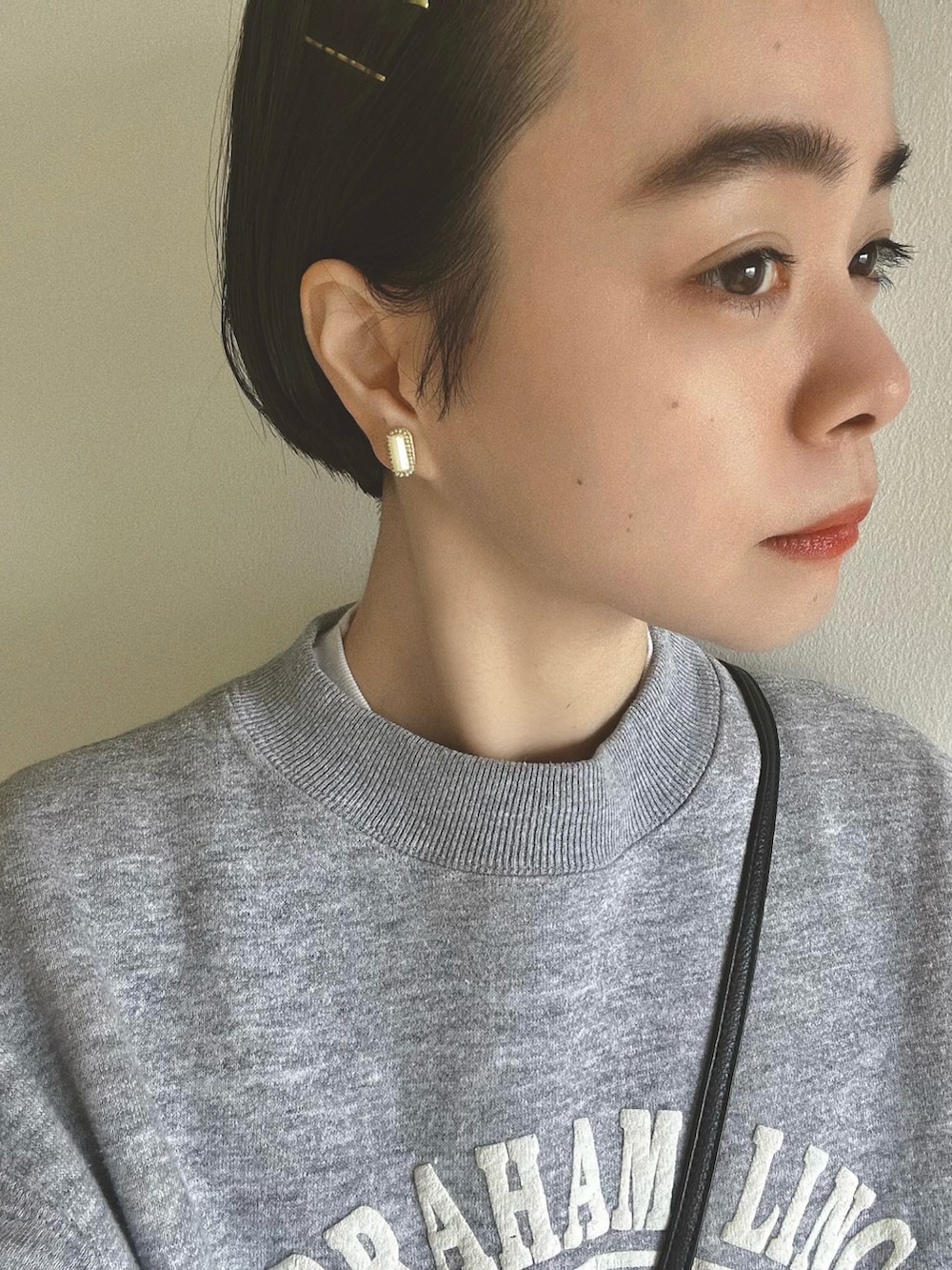 ホワイト系のスカート、ブラック系のバッグ、ブラック系のブーツを着用したレディースの春コーディネートの2枚目の写真