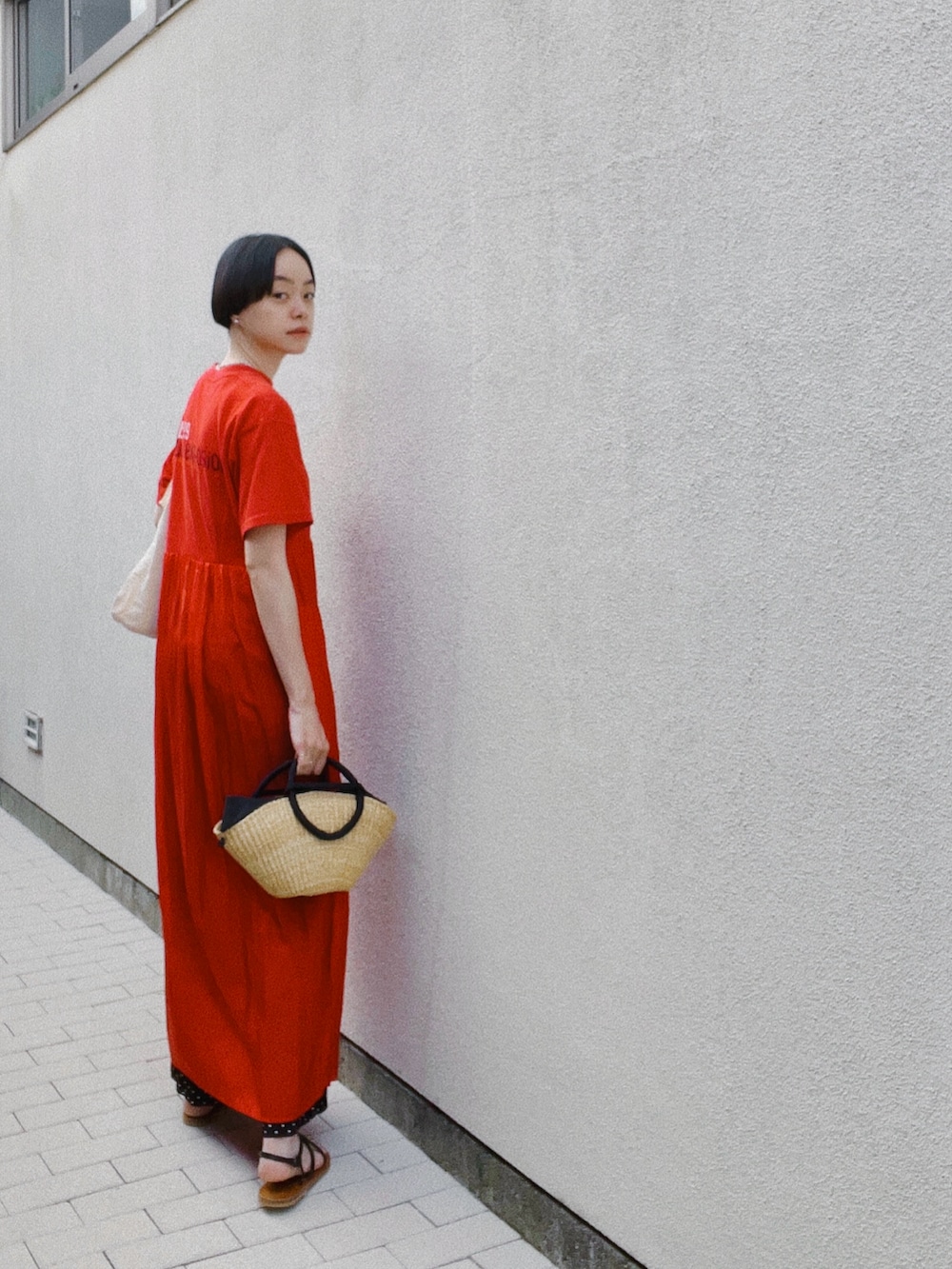 ブラック系のサンダル、ブラック系のかごバッグ、レッド系のワンピース/ドレスを着用したレディースの夏コーディネートの2枚目の写真