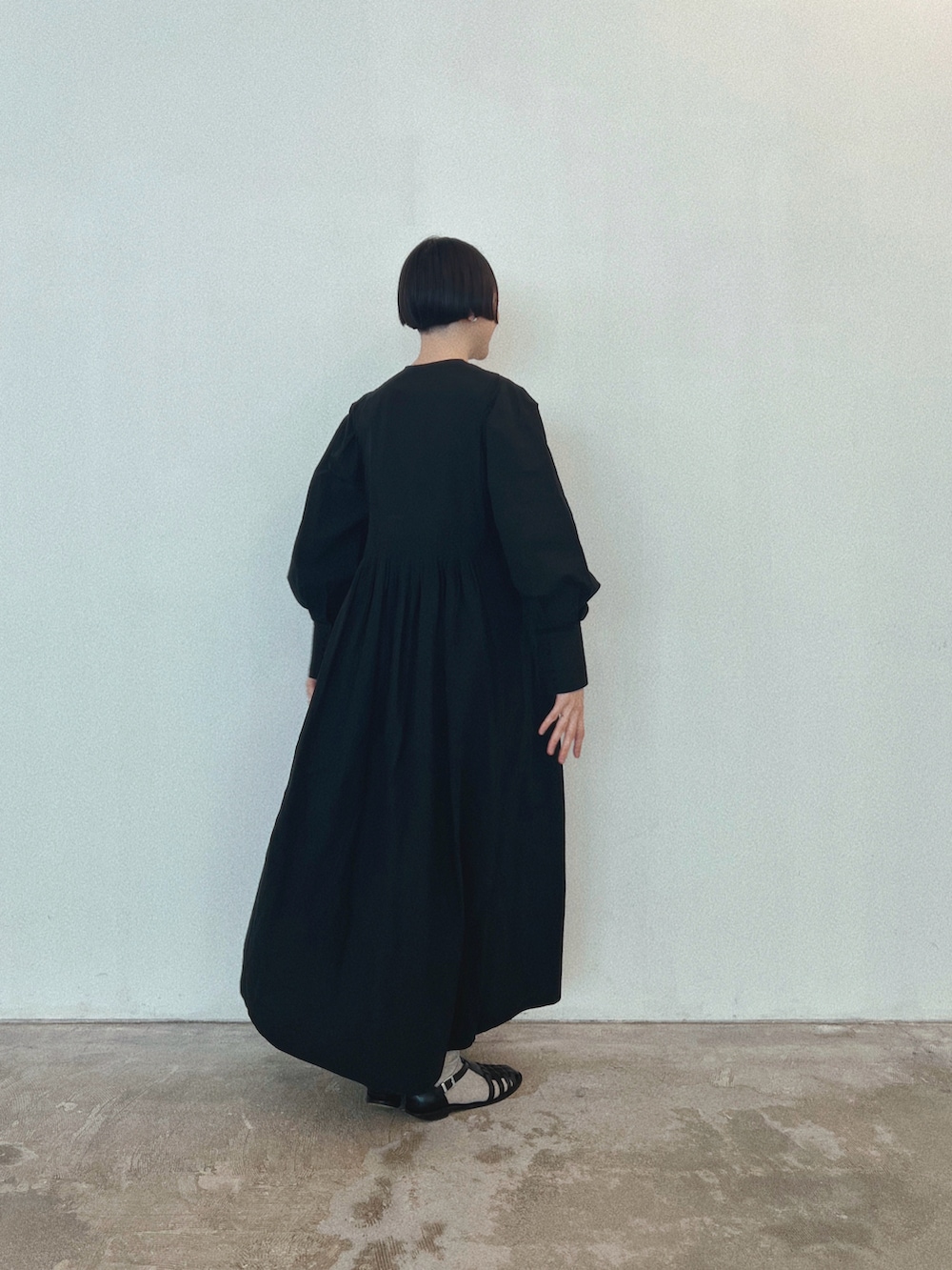 ブラック系のワンピース、ブラック系のサンダル、シルバー系のイヤリングを着用したレディースの春コーディネートの2枚目の写真