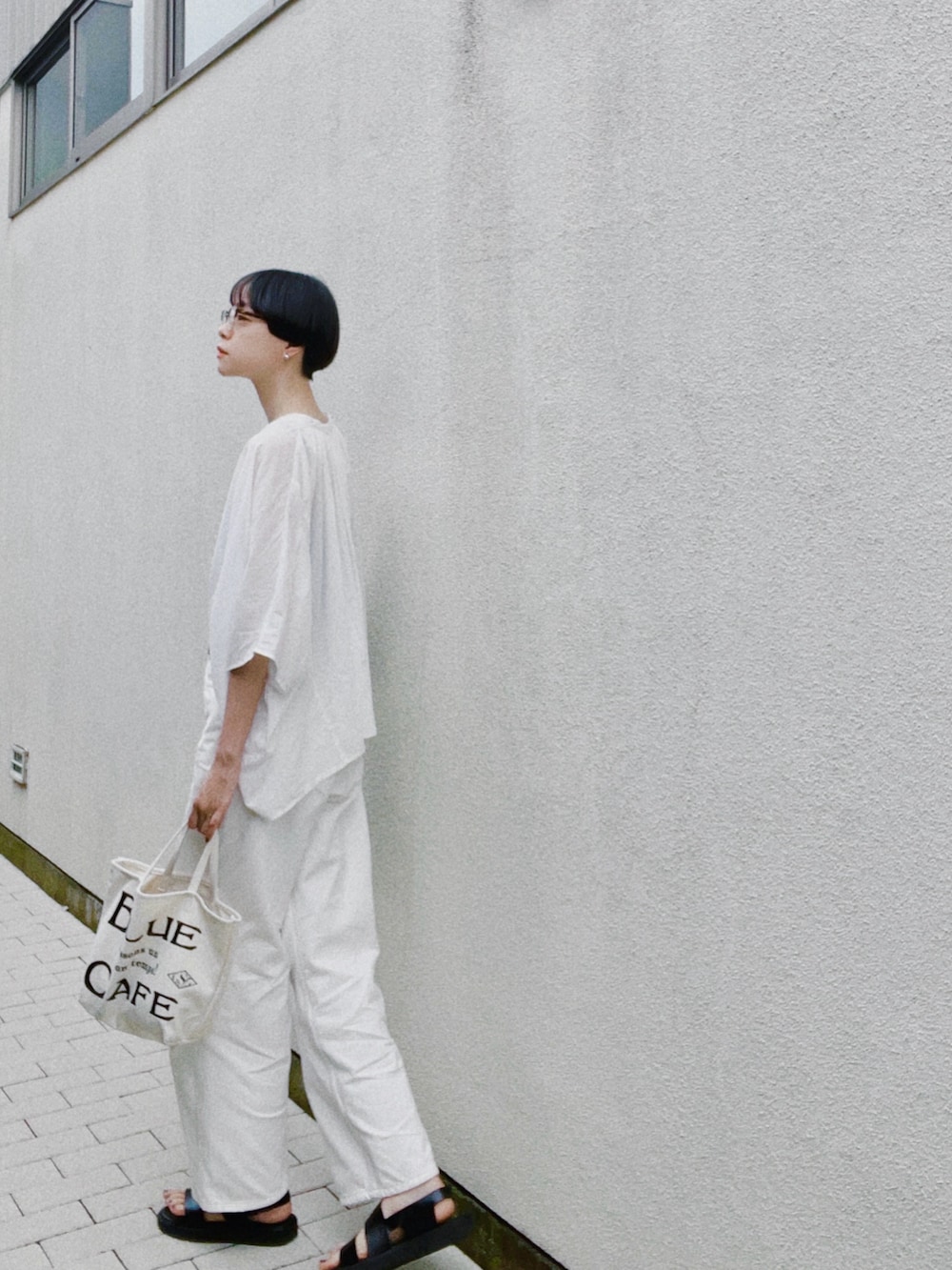 ブラック系のサンダル、ホワイト系のシャツ/ブラウス、ホワイト系のデニムパンツを着用したレディースの夏コーディネートの2枚目の写真