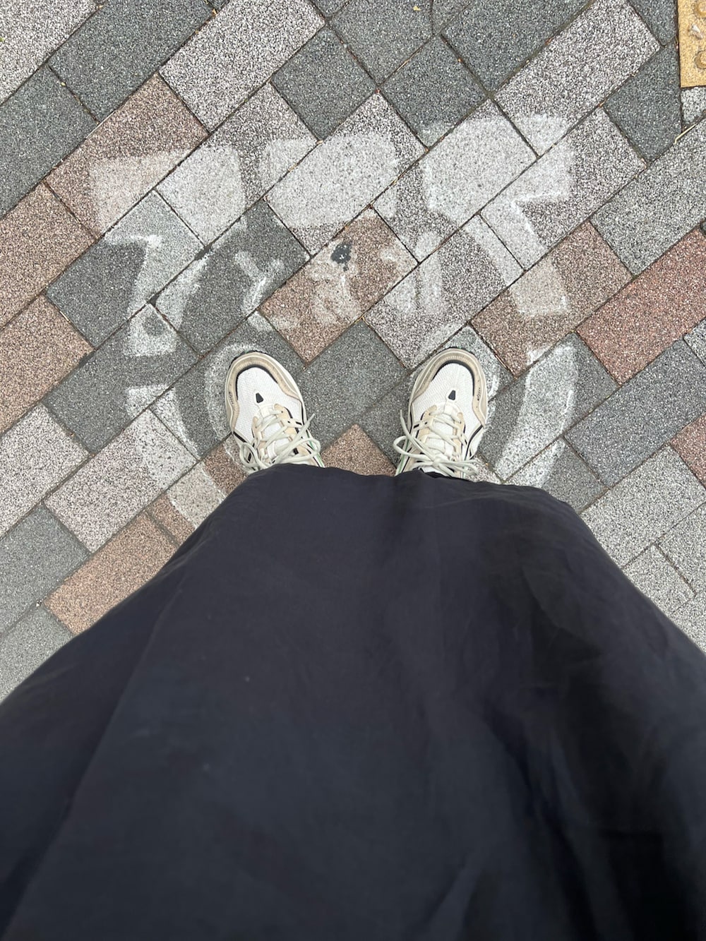 ブラック系のワンピース/ドレス、オレンジ系のバックパック/リュック、ベージュ系のTシャツ/カットソーを着用したレディースの春コーディネートの2枚目の写真