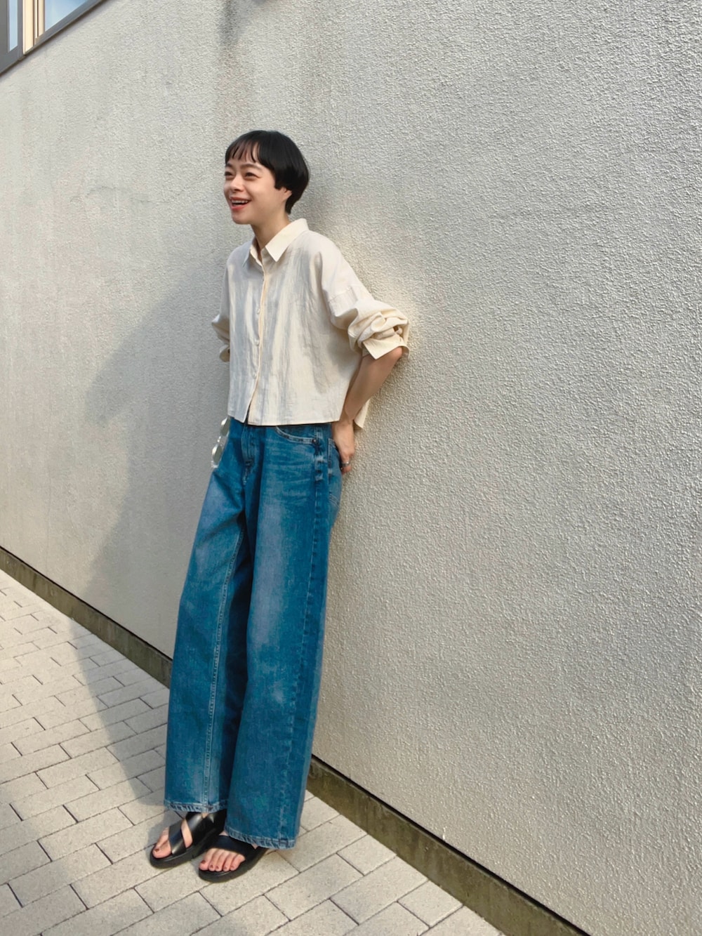 ブルー系のデニムパンツ、ベージュ系のシャツ/ブラウス、ブラック系のサンダルを着用したレディースの夏コーディネートの2枚目の写真