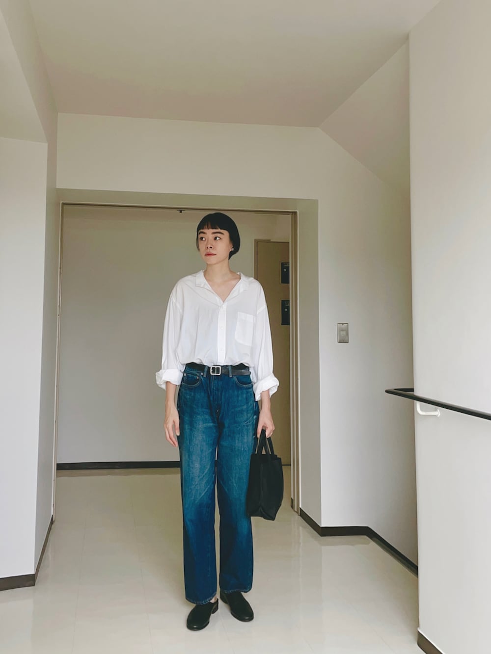 ブルー系のデニムパンツ、ブラック系のトートバッグ、シルバー系のイヤリングを着用したレディースの秋コーディネートの2枚目の写真