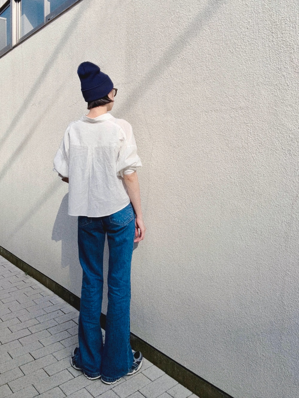 ホワイト系のシャツ/ブラウス、ブルー系のデニムパンツ、ブラック系のスニーカーを着用したレディースの夏コーディネートの2枚目の写真