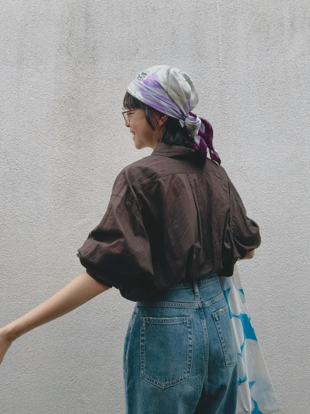 ブルー系のデニムパンツ、ブラウン系のシャツ/ブラウス、ブルー系のエコバッグ/サブバッグを着用したレディースの夏コーディネートの2枚目の写真