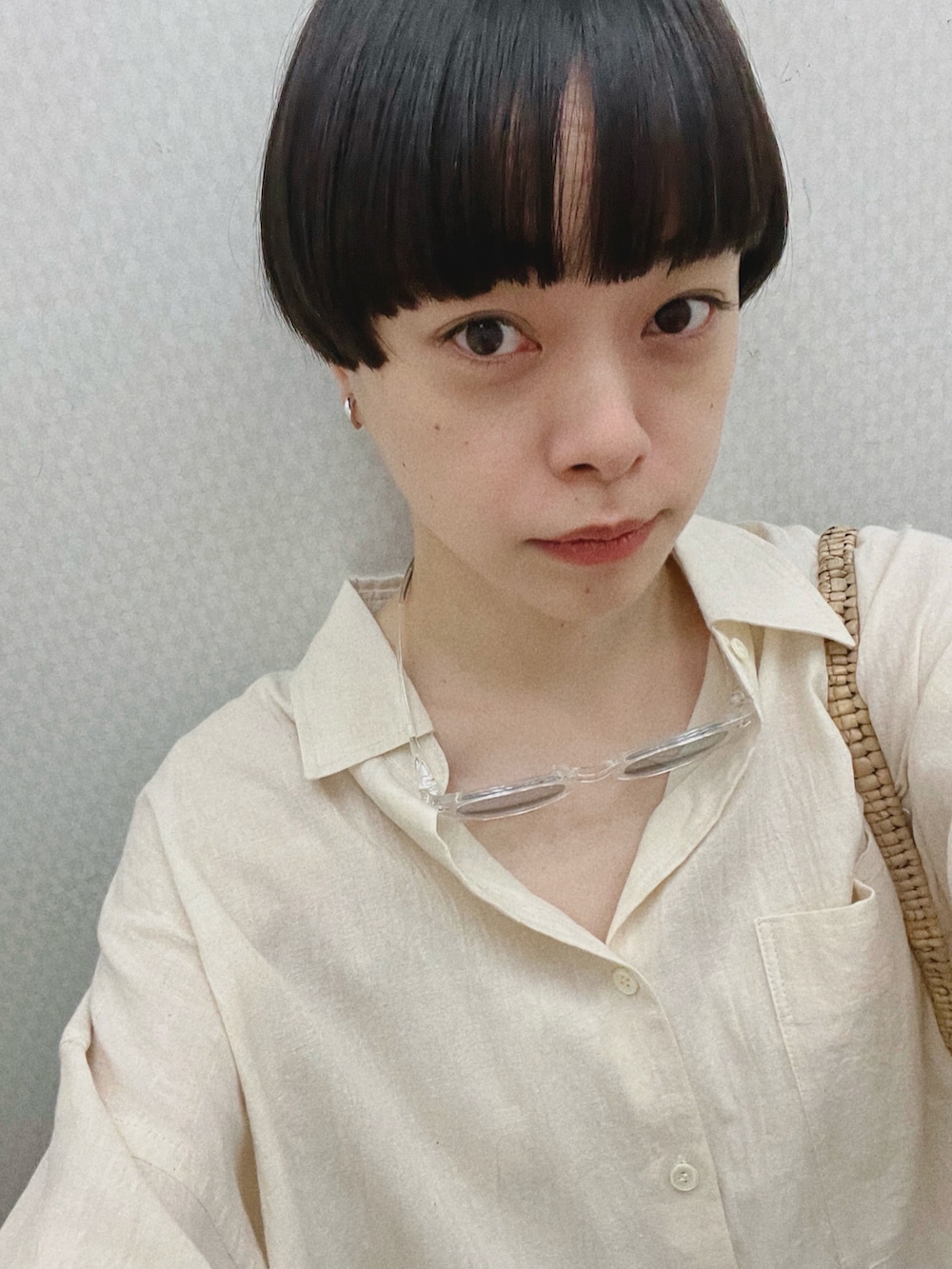 ベージュ系のシャツ/ブラウス、ベージュ系のかごバッグ、ブルー系のデニムパンツを着用したレディースの夏コーディネートの3枚目の写真