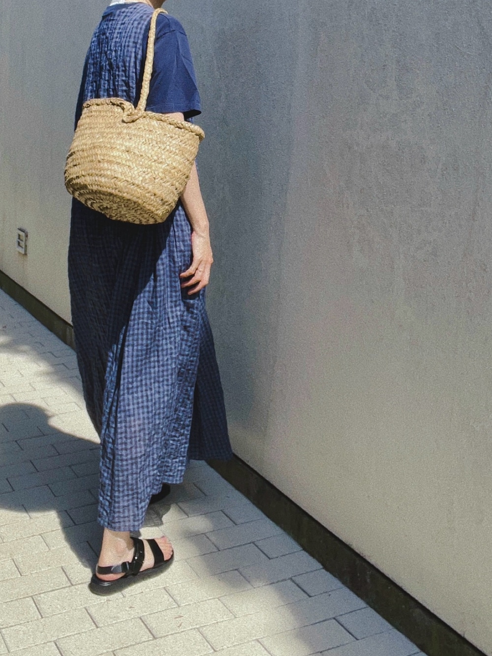 ブルー系のワンピース、ベージュ系のかごバッグ、ブラック系のサンダルを着用したレディースの夏コーディネートの2枚目の写真