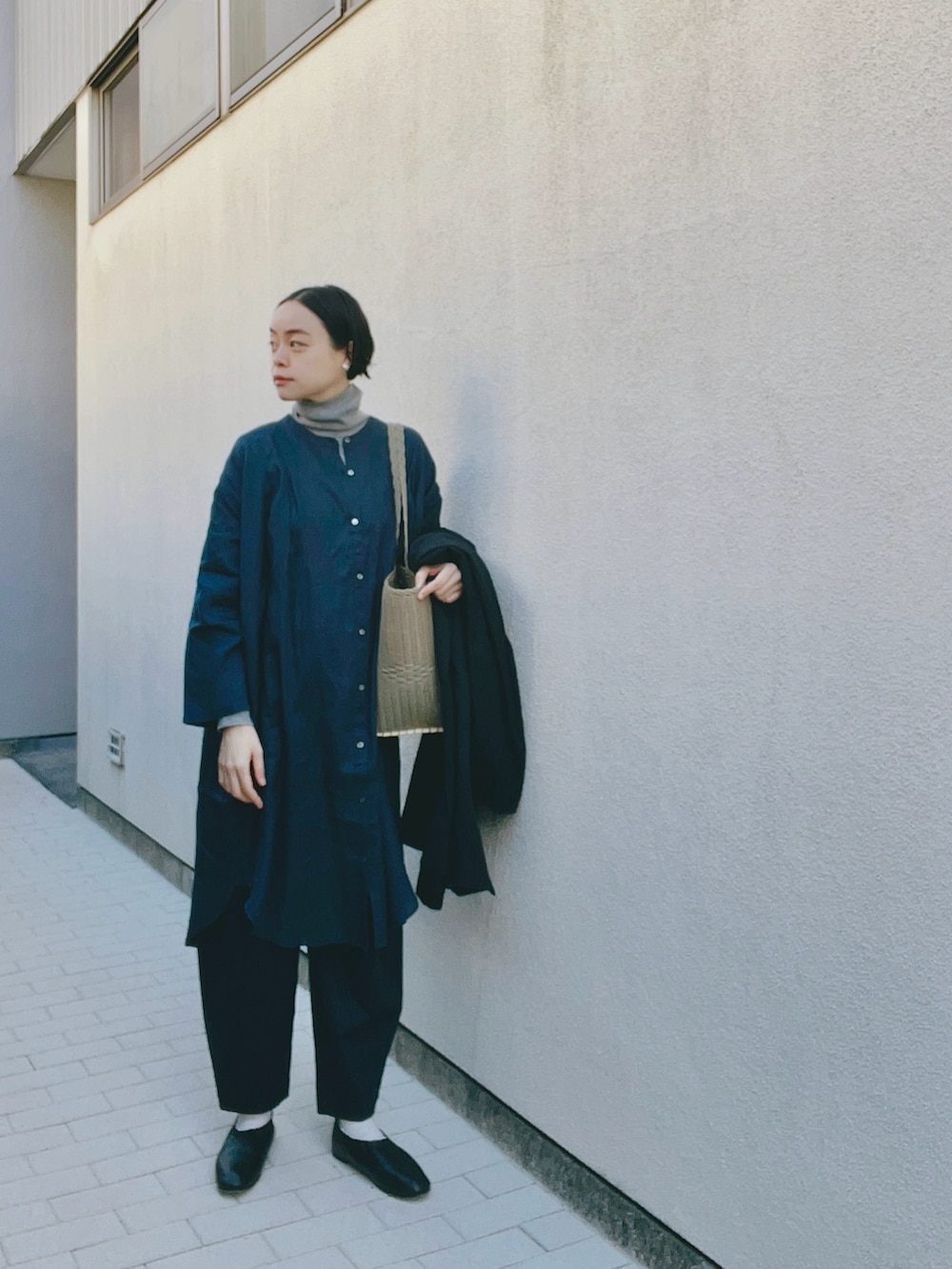 ブルー系のシャツ/ブラウス、グレー系のニット/セーター、ベージュ系のかごバッグを着用したレディースの冬コーディネートの2枚目の写真