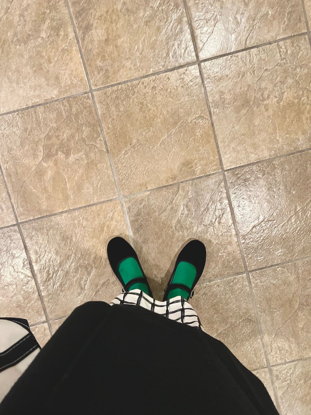 ブラック系のピーコート、ブラック系のトートバッグ、ベージュ系のスカートを着用したレディースの冬コーディネートの3枚目の写真