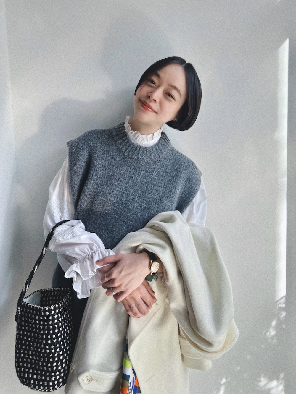 グレー系のベスト、ホワイト系のジャケット/アウター、ホワイト系のパンツを着用したレディースの冬コーディネートの2枚目の写真