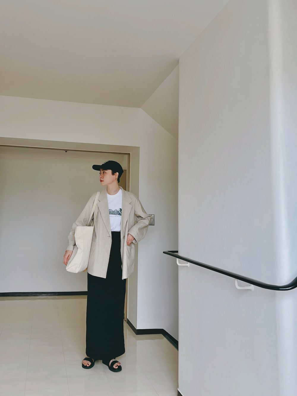 ホワイト系のTシャツ/カットソー、ベージュ系のテーラードジャケット、ブラック系のスカートを着用したレディースの春コーディネートの2枚目の写真