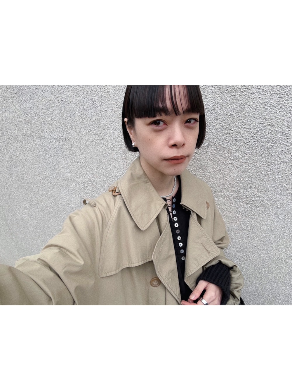 ベージュ系のトレンチコート、ブラック系のワンピース/ドレス、ブラック系のカーディガン/ボレロを着用したレディースの春コーディネートの2枚目の写真