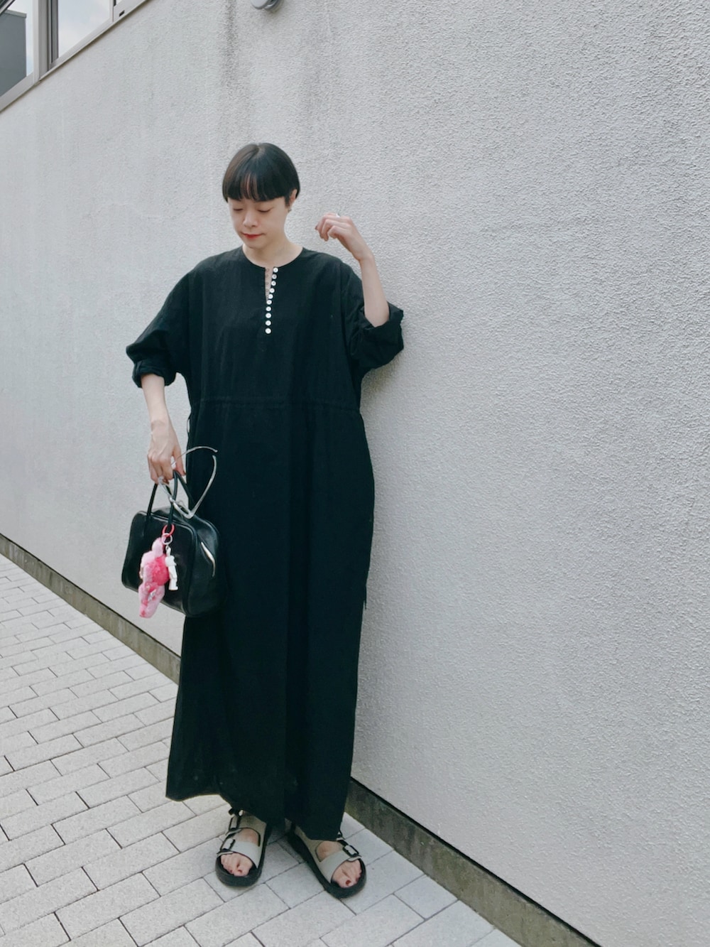 ブラック系のワンピース/ドレス、ベージュ系のサンダル、ブラック系のバッグを着用したレディースの夏コーディネートの2枚目の写真