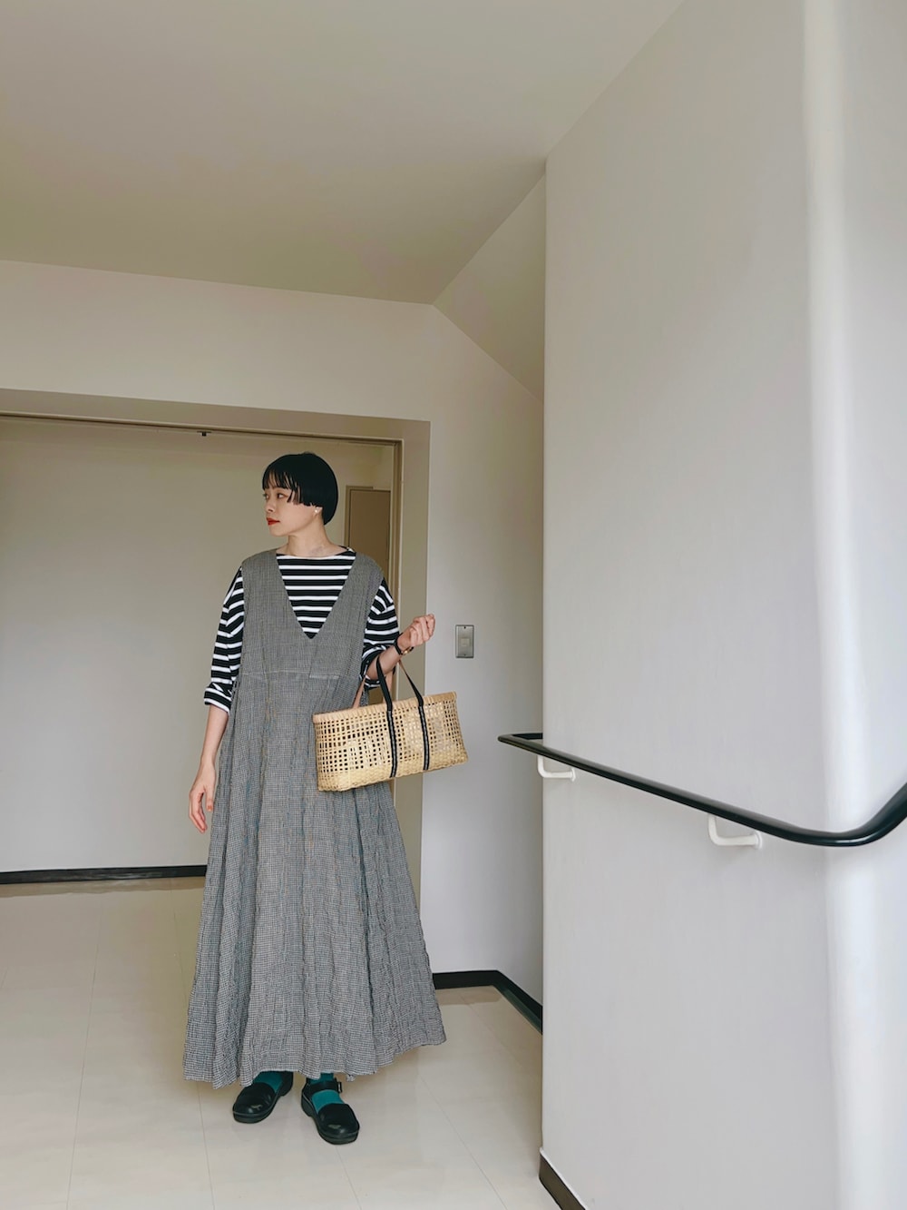 ブラック系のトップス、ホワイト系のワンピース、ブラック系のかごバッグを着用したレディースの夏コーディネートの2枚目の写真