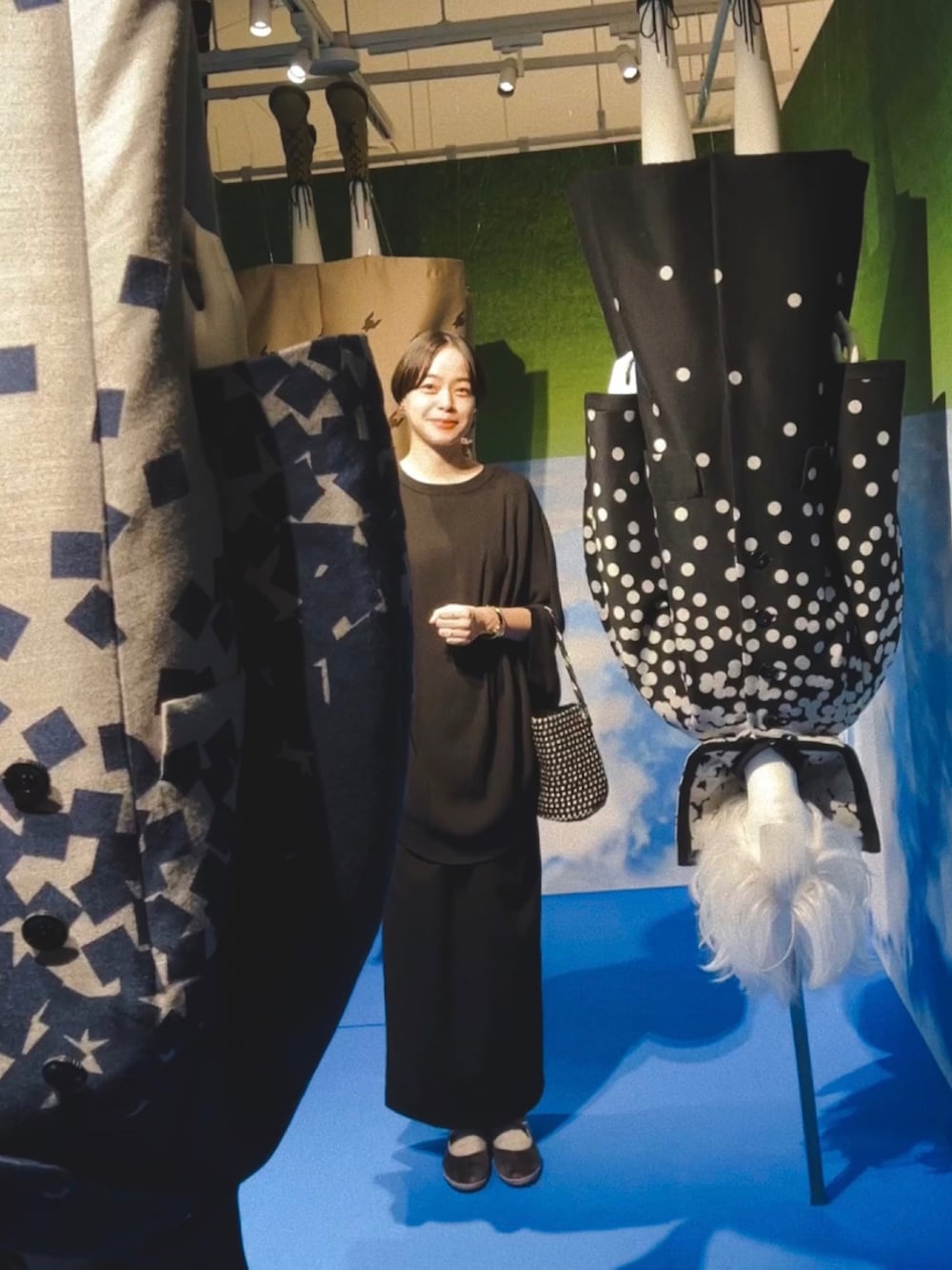 ブラック系のトップス、ブラック系のスカート、ブラック系のバッグを着用したレディースの秋コーディネートの2枚目の写真